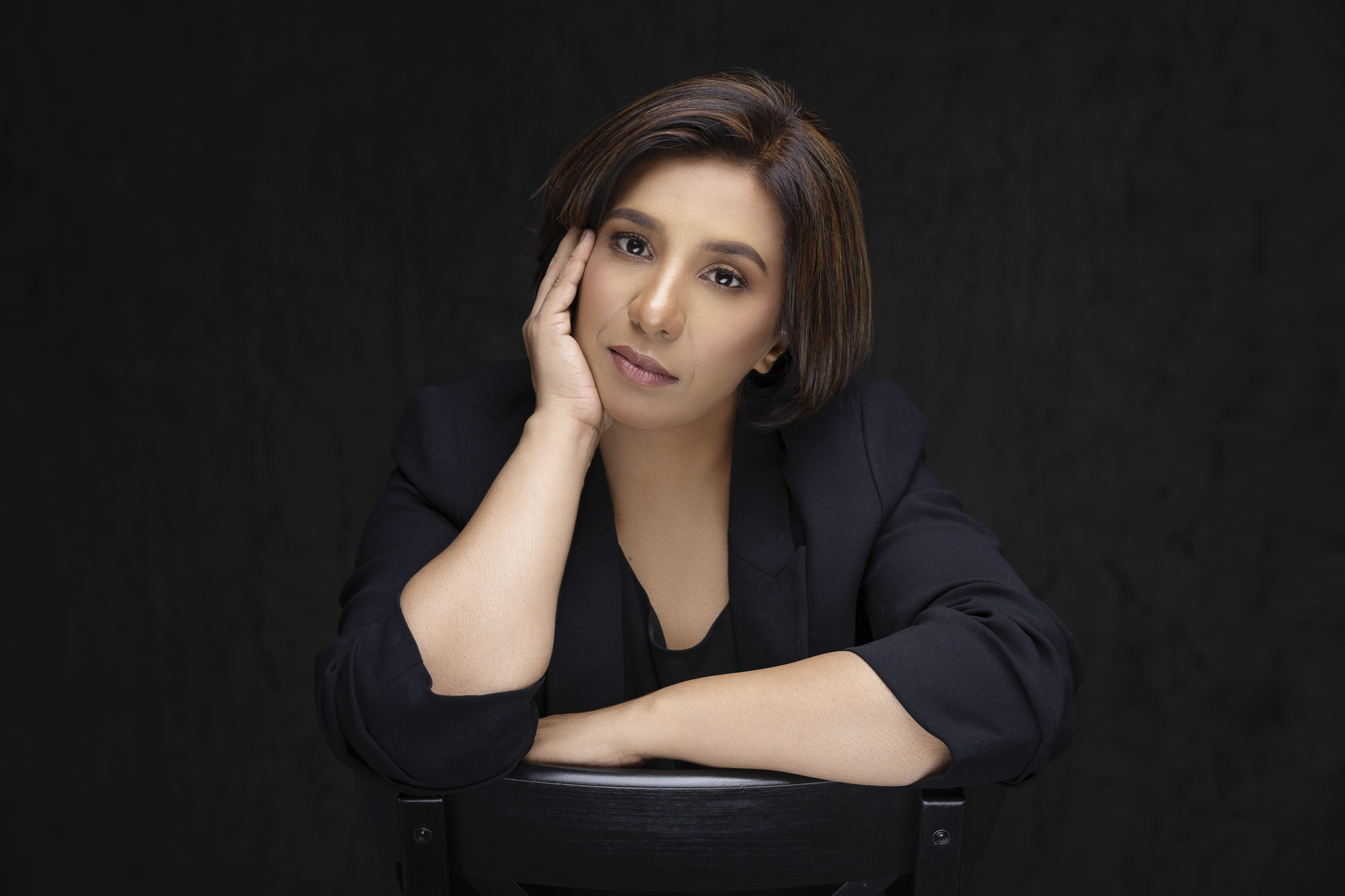 Portrait of a woman leaning on a chair and supporting her chin.